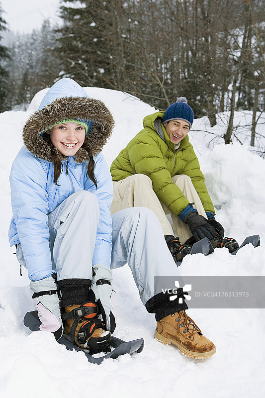 年轻夫妇在森林旁系雪鞋图片素材