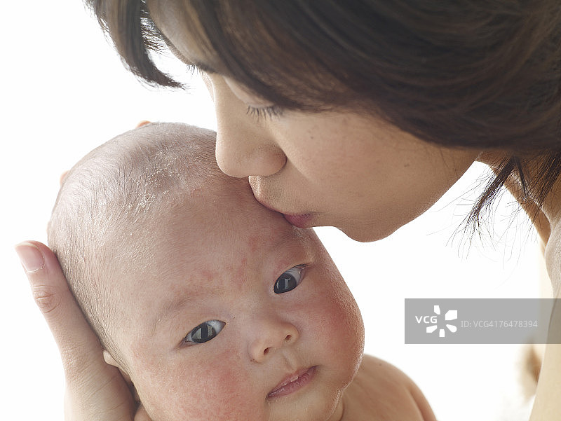 一位女士亲吻新生婴儿的头部图片素材