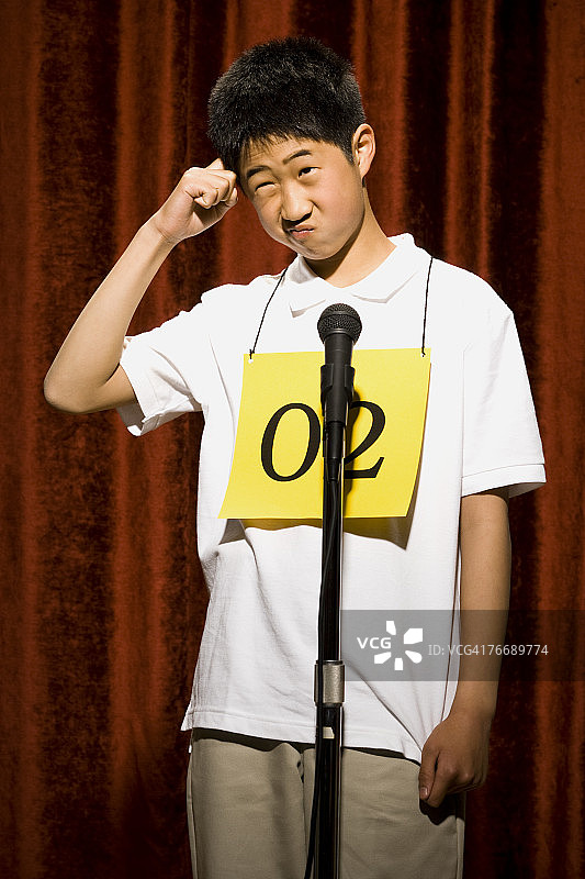 男孩在麦克风前挠头图片素材