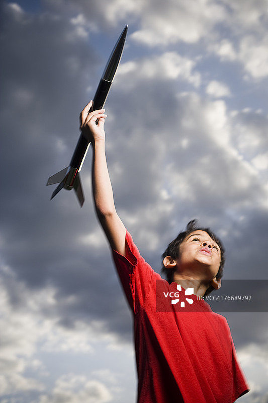 男孩在多云的户外玩玩具火箭，低角度拍摄图片素材