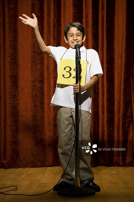 男孩选手在麦克风前挥手微笑图片素材