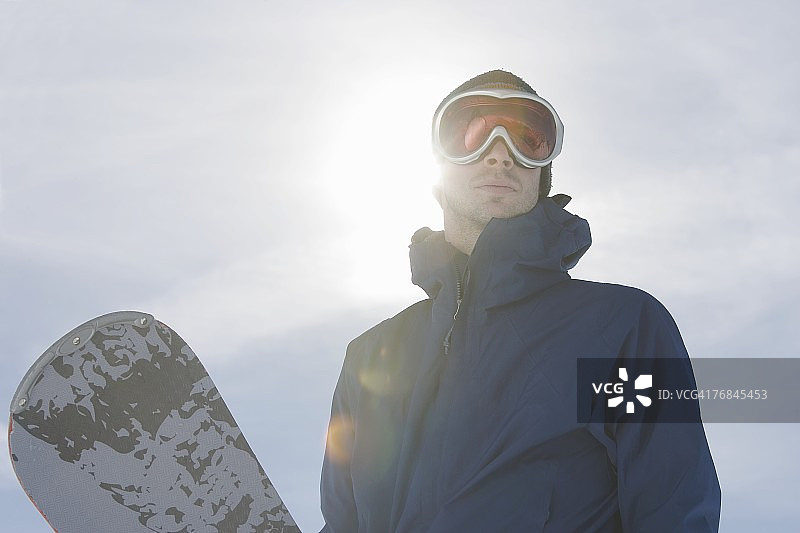 阳光下拿着滑雪板的男人肖像图片素材