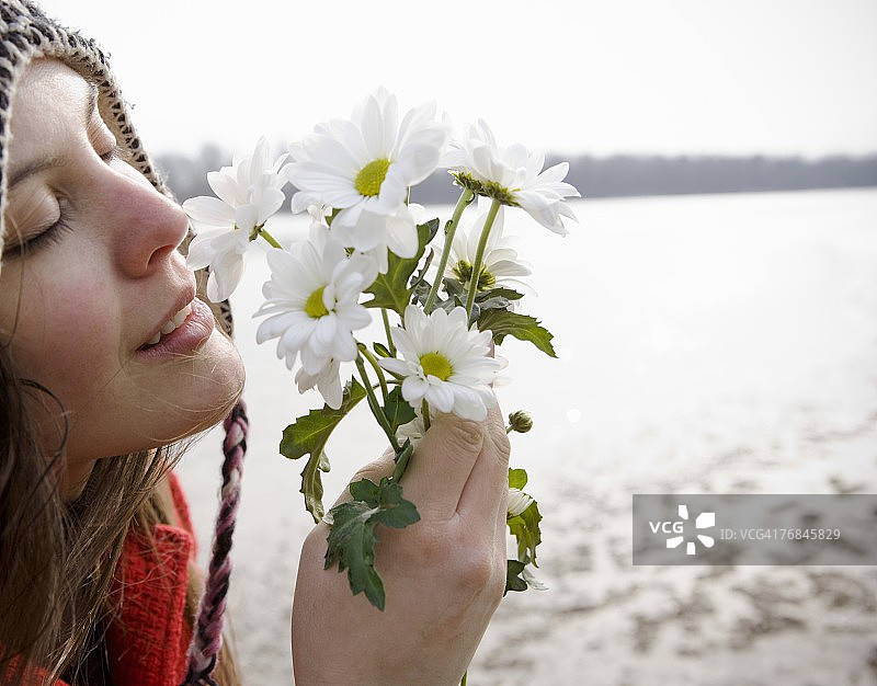 户外手捧鲜花，闭着眼睛的年轻女人图片素材