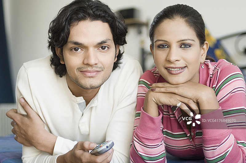 躺在床上看电视的年轻夫妇肖像图片素材