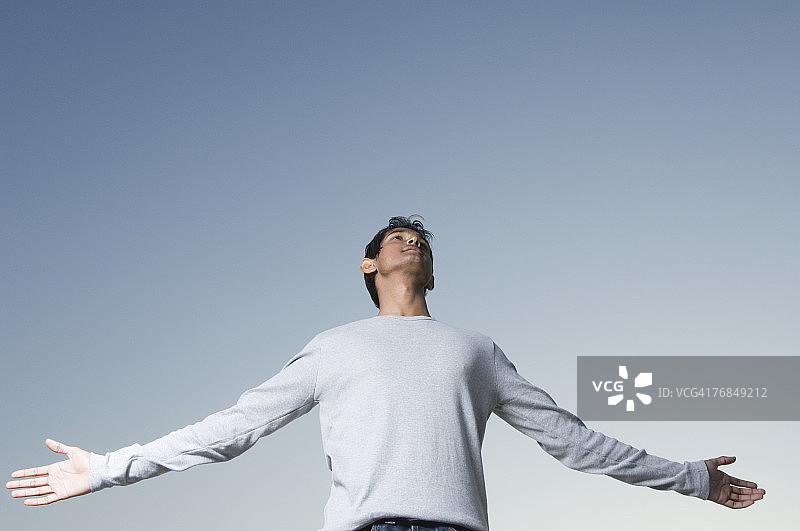 低角度拍摄的张开双臂的年轻男人图片素材