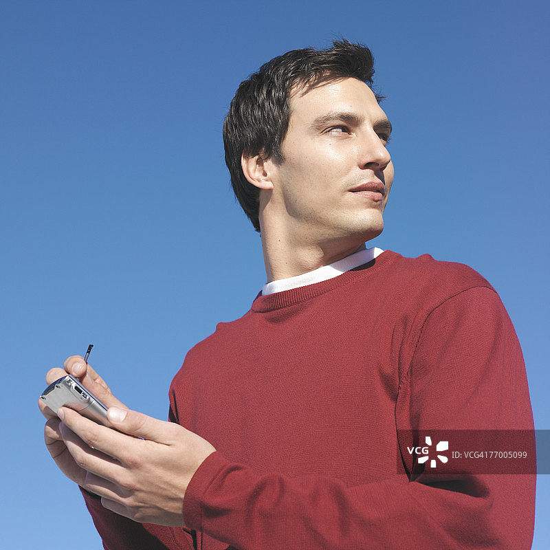 在户外用掌上电脑写笔记，回头看的年轻男人（特写，低角度）图片素材