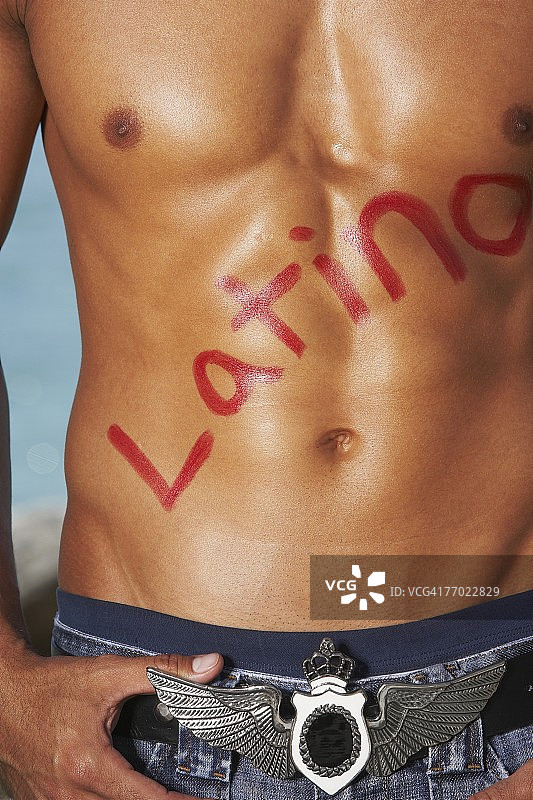 裸着上身的年轻男子胸前写着“Latino”的中段照片图片素材