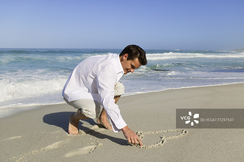 男人在沙滩上画心图片素材