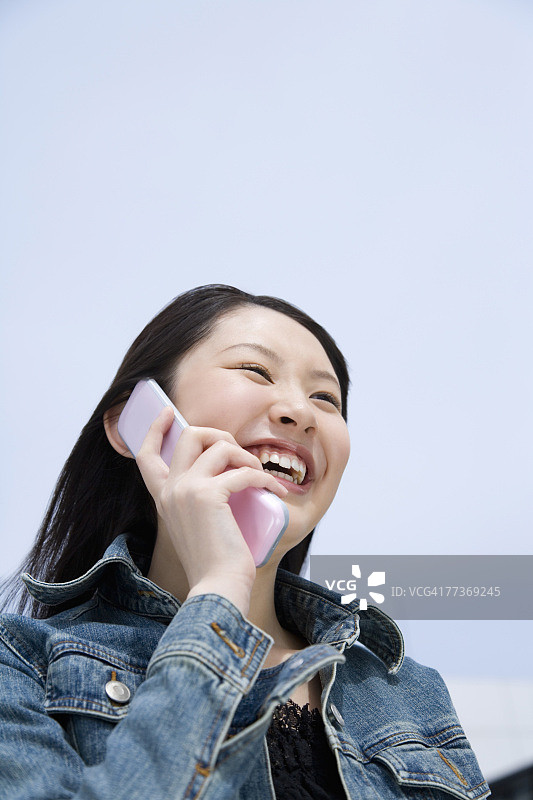 在日本蓝天下使用手机的女人（低角度）图片素材
