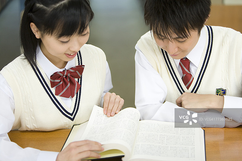 青少年情侣在图书馆里看书，面带微笑图片素材