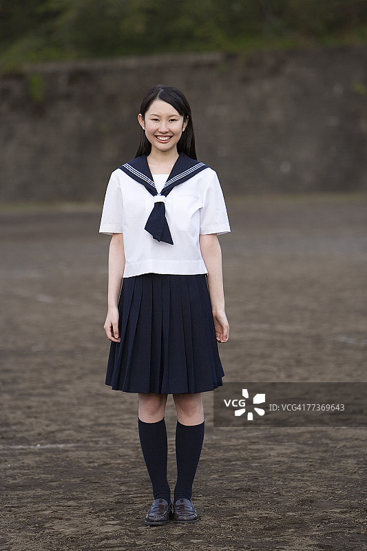 站在校园里，微笑并看着镜头的青少年女孩肖像图片素材