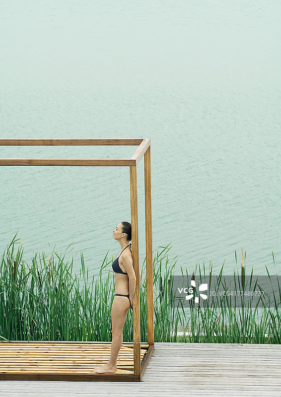 穿着比基尼站在湖边木结构建筑中的女人图片素材