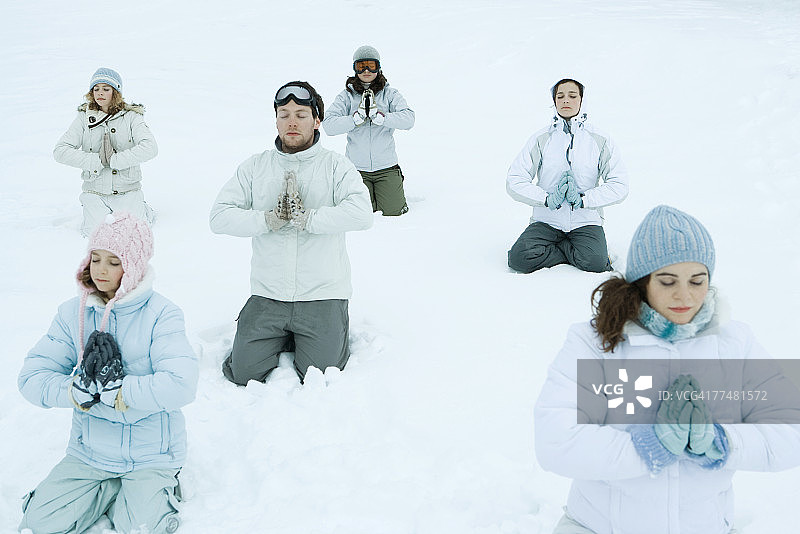 在雪地里跪着，双手紧握，闭着眼睛的一群人图片素材