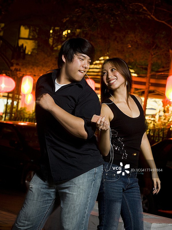 夫妇在户外跳舞微笑，听MP3播放器图片素材