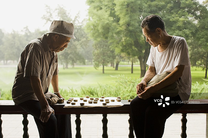 两个男人坐在户外玩棋盘游戏图片素材