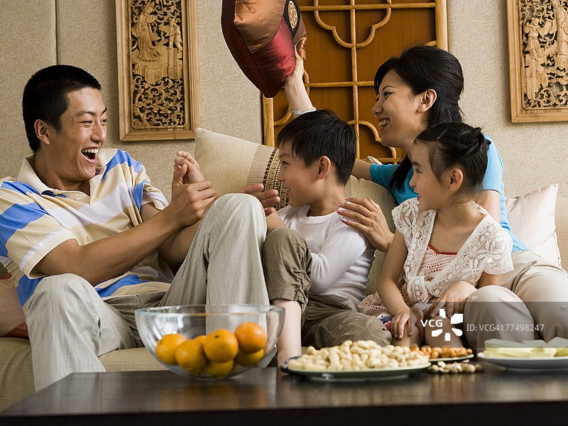 一家人在沙发上进行枕头大战，欢声笑语图片素材