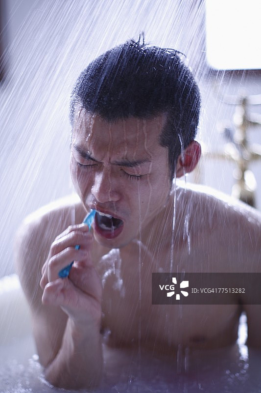 坐在淋浴下刷牙的男人图片素材