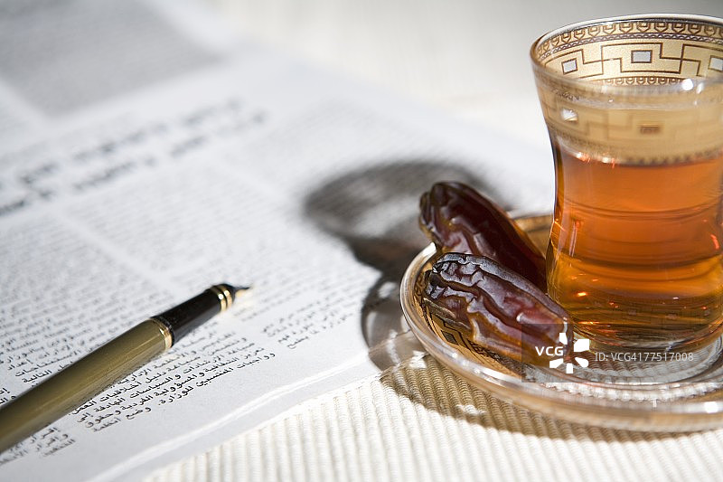 报纸、笔、阿拉伯茶和枣，阿拉伯联合酋长国迪拜图片素材