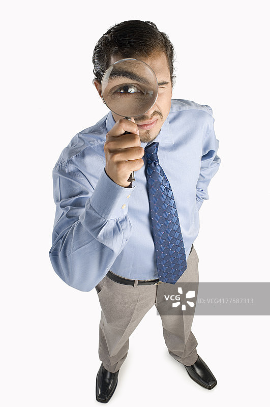 透过放大镜看的年轻男人，肖像，升高视角图片素材