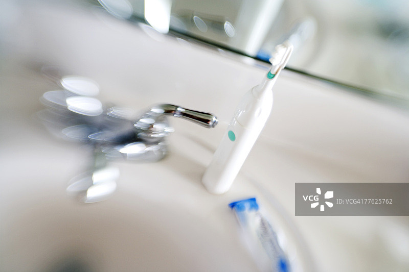 模糊的浴室水槽与蓝白色电动牙刷图片素材