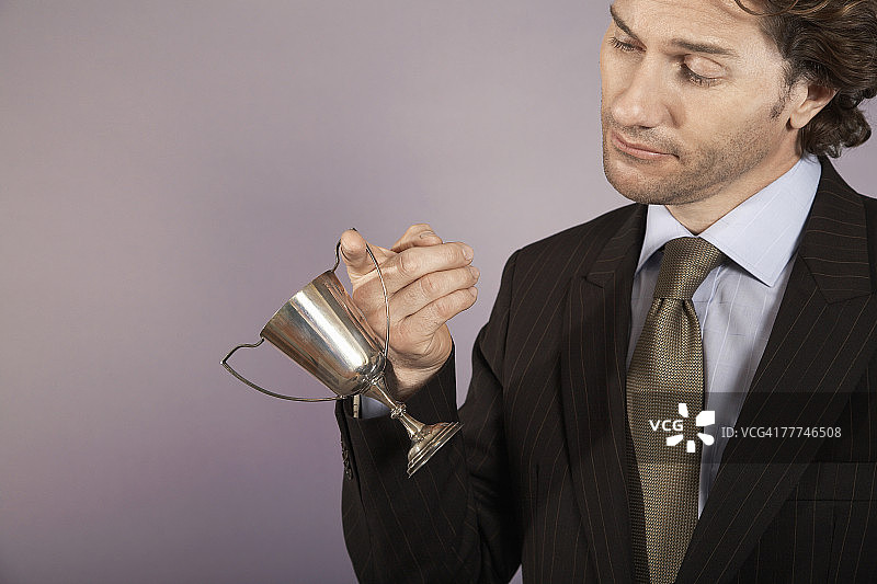 商务人士手持迷你奖杯图片素材