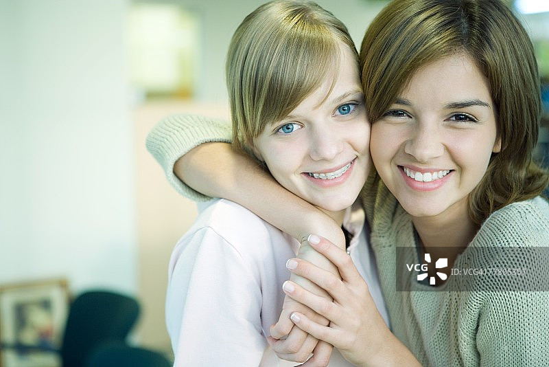 两个年轻朋友对着镜头脸贴脸搂肩微笑图片素材