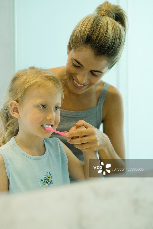 女性帮助小女孩刷牙图片素材