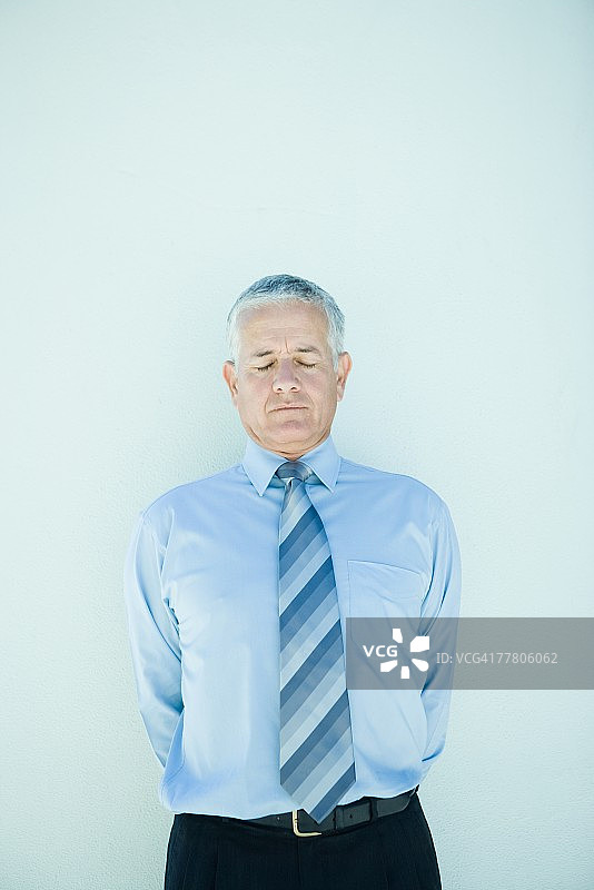 年长的商人站立，双手背后，闭着眼睛图片素材