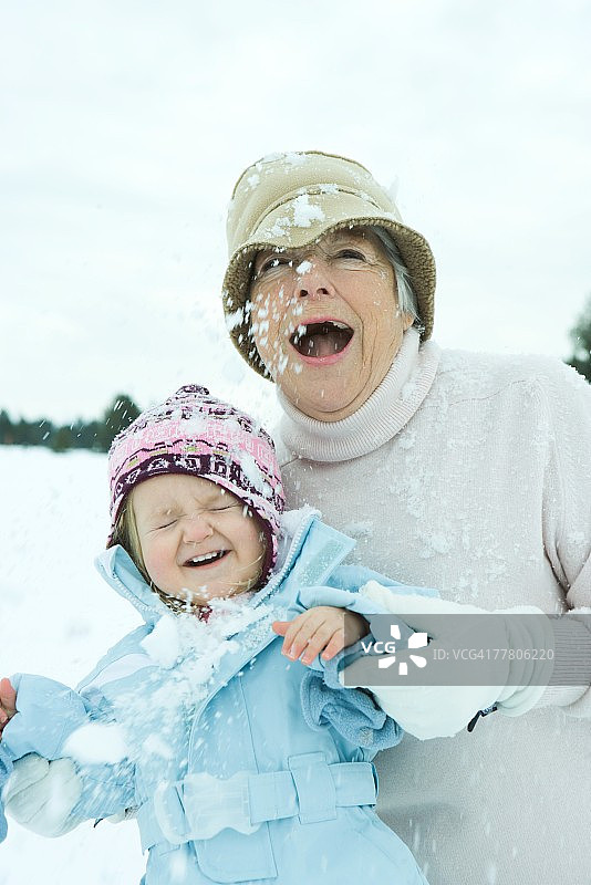祖母和孙女被雪球击中，微笑图片素材