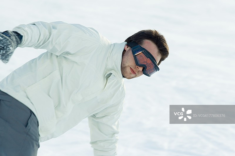 年轻男子身着滑雪服在雪地里弯腰图片素材