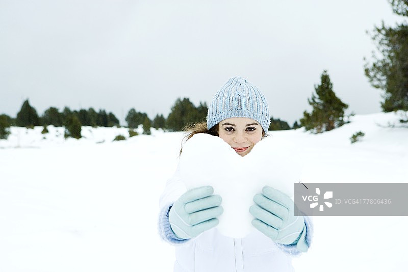 年轻女人在雪景中手捧雪制的心图片素材
