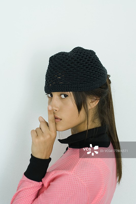 少女回头看向镜头，手指放在嘴唇上图片素材
