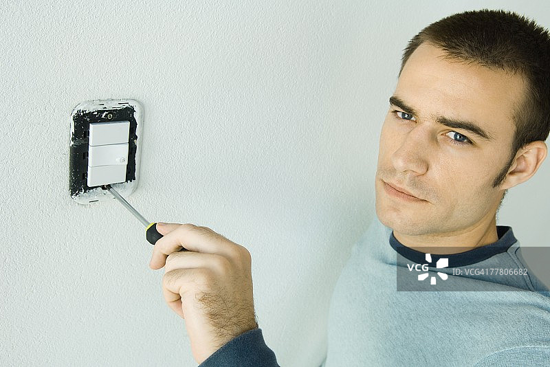 男人正在拆卸电灯开关盖图片素材