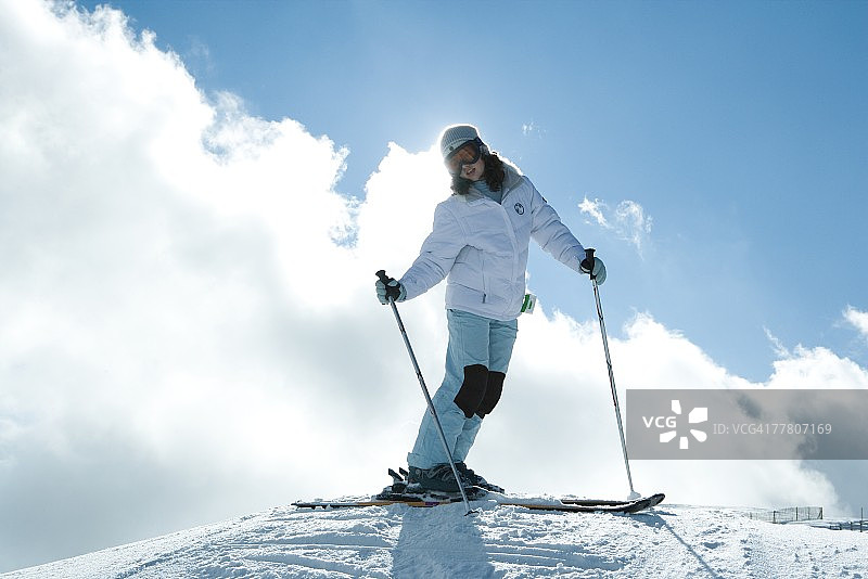 年轻女子站在滑雪坡顶端的全身像图片素材