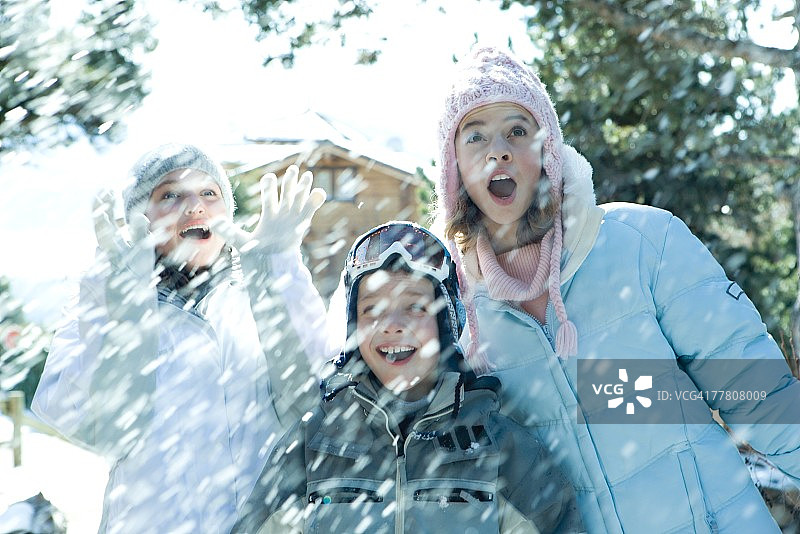 年轻的朋友们站在飘落的雪中，微笑，半身照图片素材