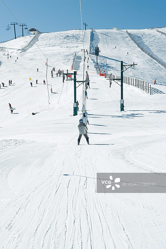 年轻滑雪者乘坐滑雪缆车（后视图）图片素材