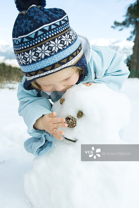 幼儿女孩堆雪人，弯腰图片素材