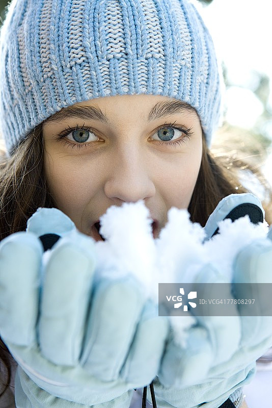 看着镜头，手捧雪花的少女图片素材