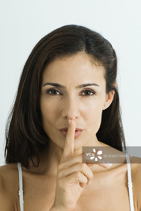 女人手指放在嘴唇上，看着镜头图片素材