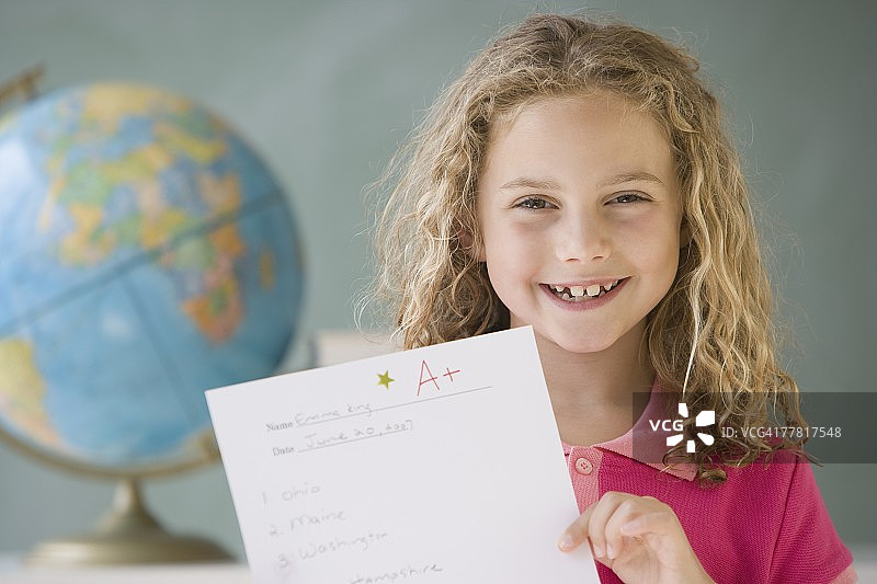 女孩在教室展示A+试卷图片素材