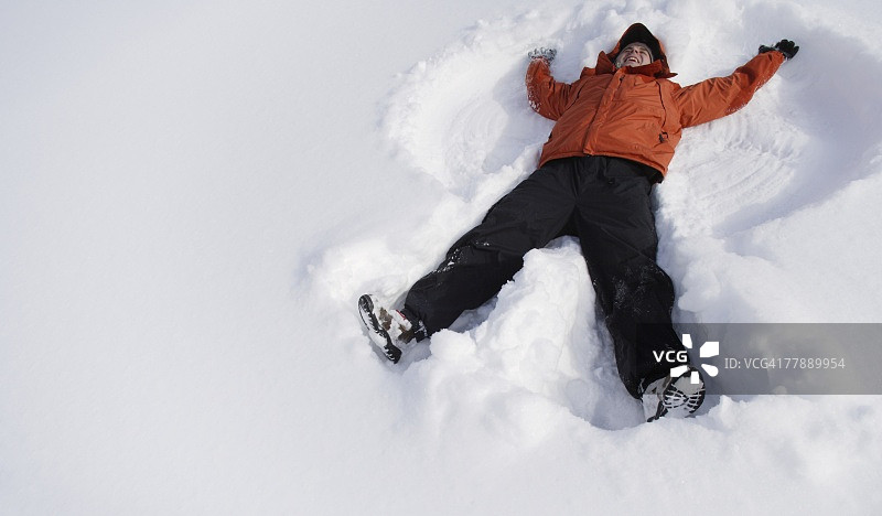 男孩在雪地里制作雪天使图片素材