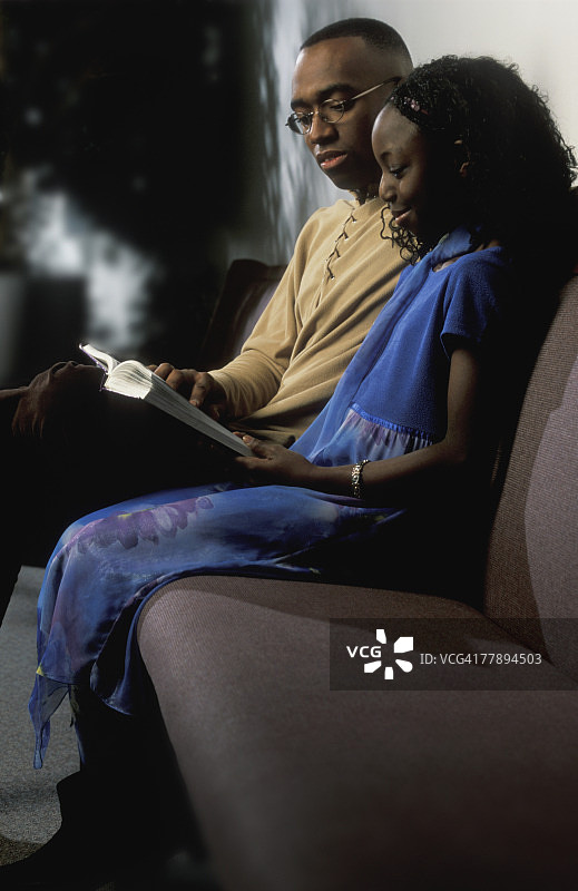 男人和女孩在沙发上读书图片素材