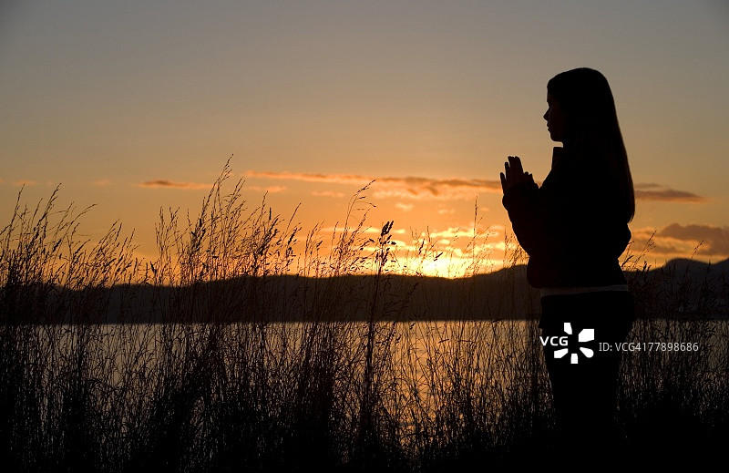 少女在日落时于海边祈祷图片素材