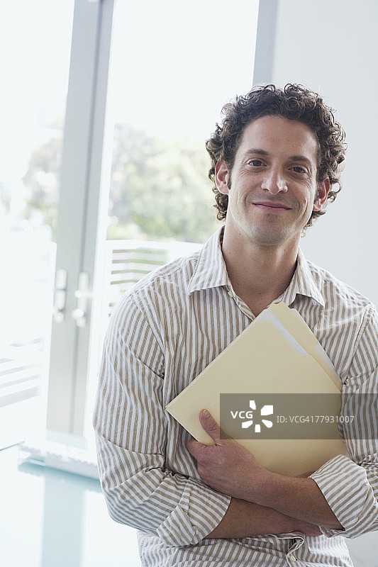 办公室里抱着文件夹的商人图片素材