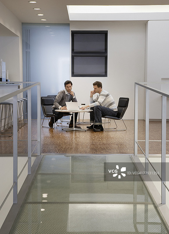 两位商人在办公室里看着笔记本电脑图片素材