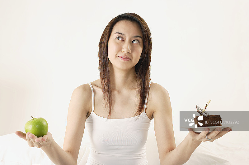 女人在蛋糕和苹果之间选择图片素材