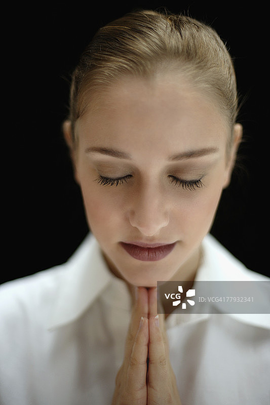 闭着眼睛，双手合十祈祷的女人图片素材