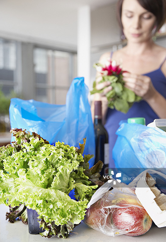 在厨房里拿着食品杂货和鲜花的女人图片素材