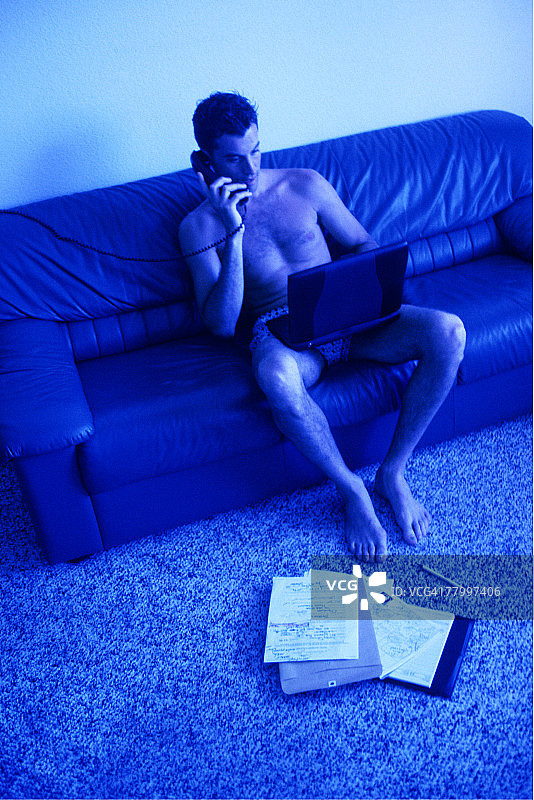 穿拳击短裤的男人在用笔记本电脑工作图片素材