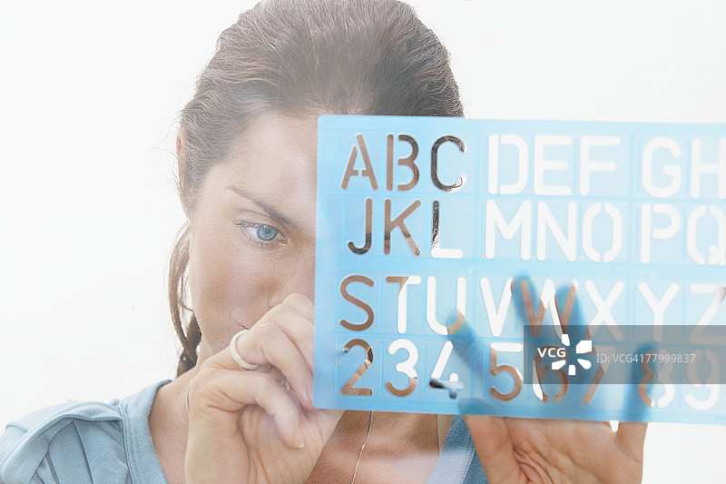 透过窗户使用绘图设备的女人特写图片素材